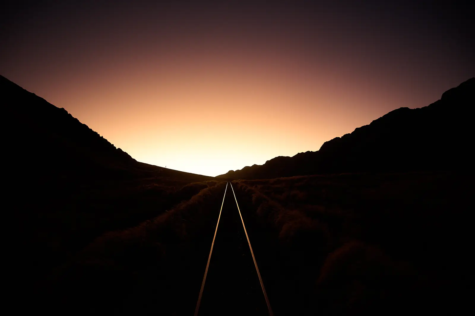 Andean train tracks vanishing into the horizon at dusk, photographed by Javier Falcón