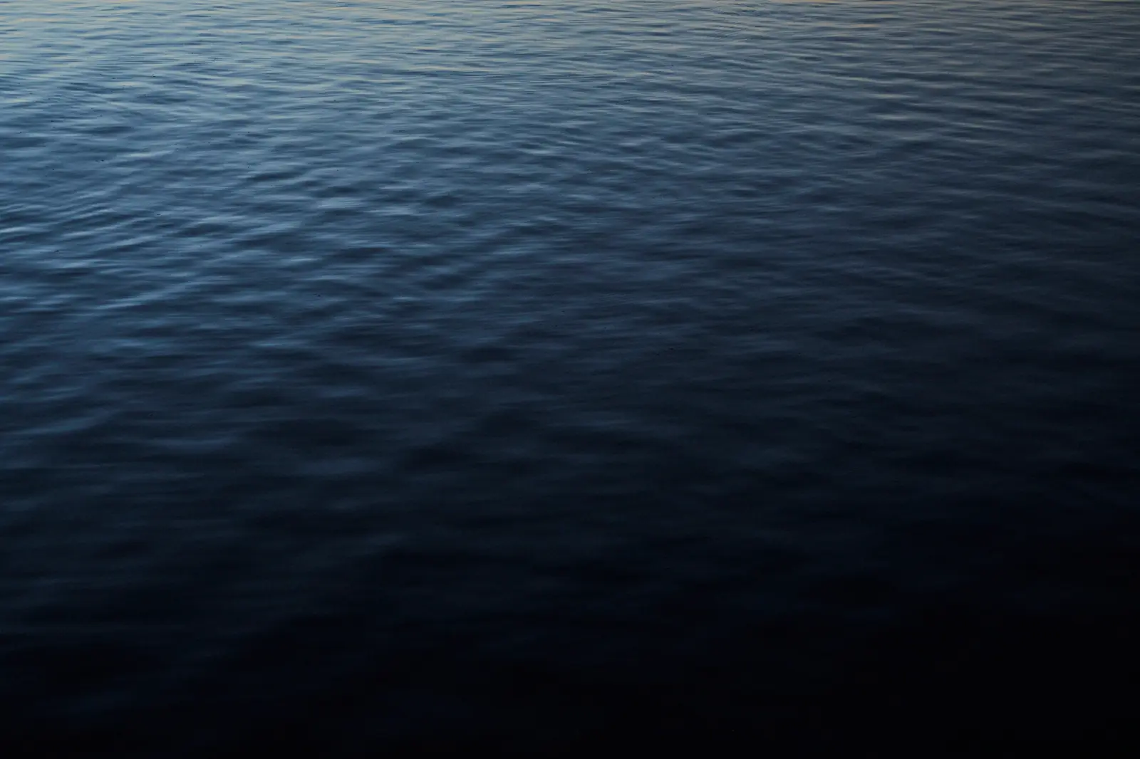 Surface of Lake Titicaca in blue tones at dawn, photographed by Javier Falcón for Belmond Andean Explorer