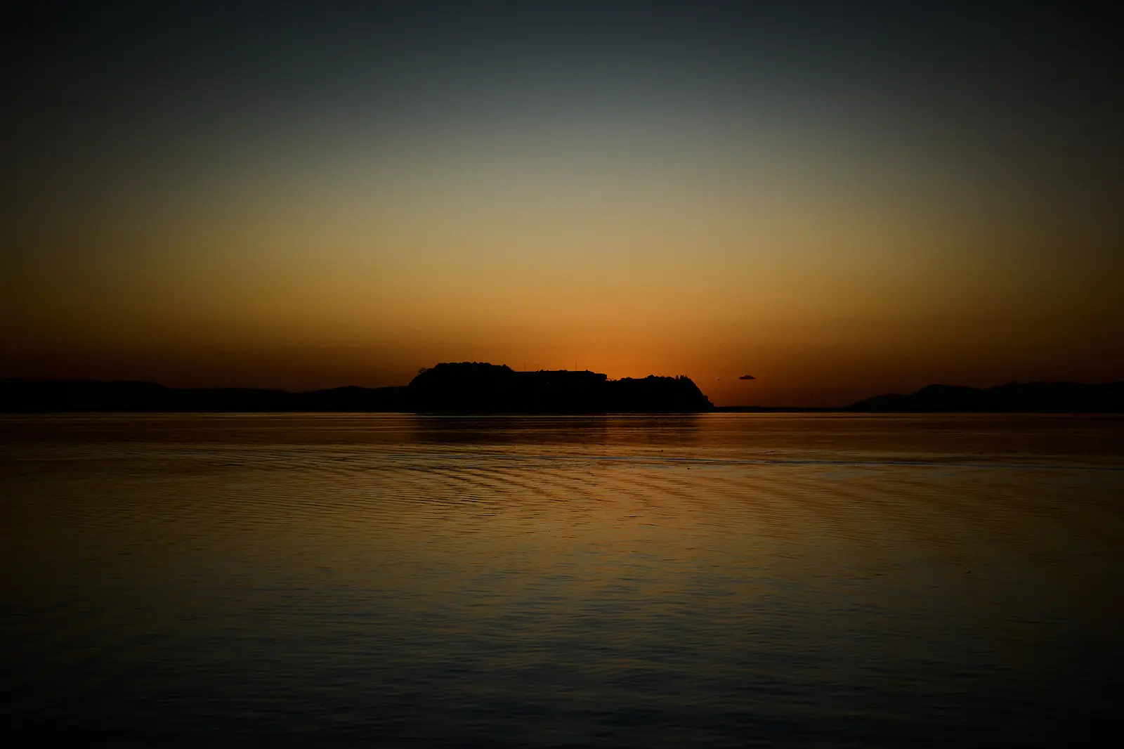 Island on Lake Titicaca against an orange sunset, photographed by Javier Falcón for Belmond Andean Explorer